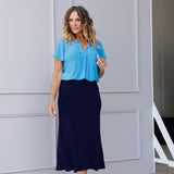 Size 12 woman wears navy Midi Skirt - a sleek, sophisticated staple design for both work and travel. Crafted in a deep blue hue, the skirt features a bias-cut design that drapes beautifully, creating a flattering, easy fluid silhouette.