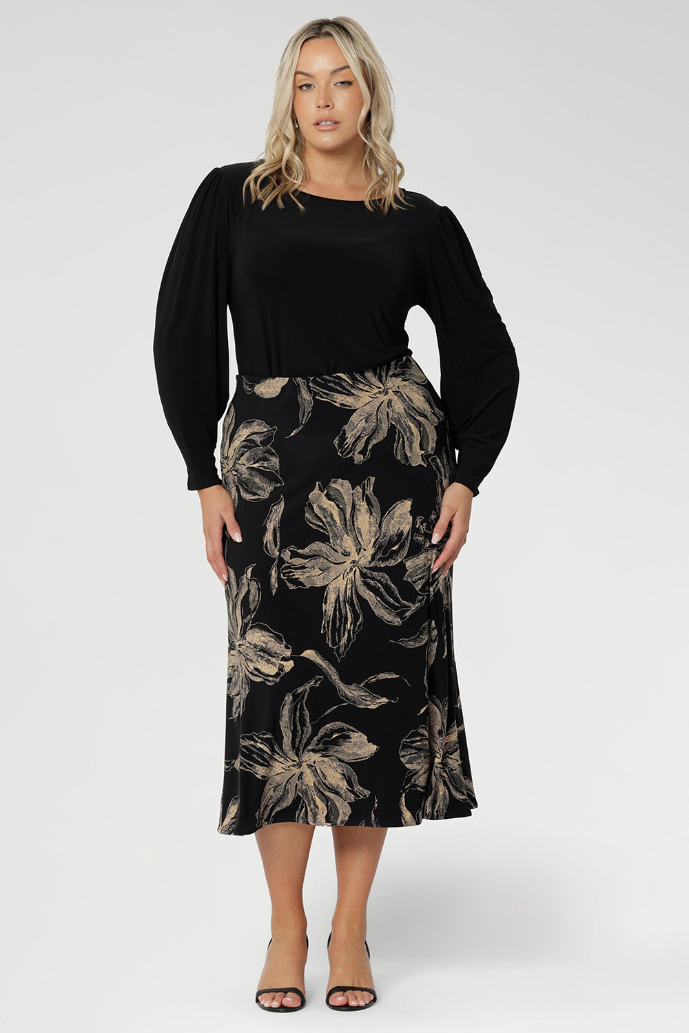 The Asher Skirt brings effortless style to your wardrobe with its easy pull-on design and soft stretch feel, crafted from our signature dry-touch jersey in classic black. Plus size model wears midi skirt with black top with bellow sleeves.