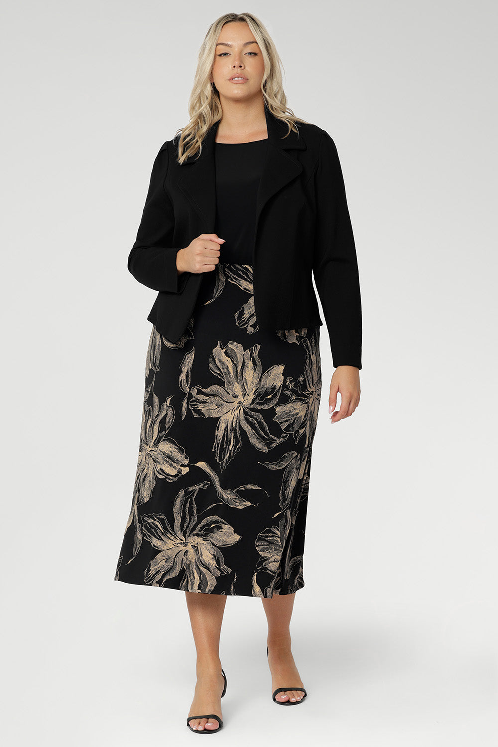 Crafted from our signature dry-touch jersey in classic black. Plus size model wears midi skirt with black top with bellow sleeves and a structured black work jacket. Creating a ready for work look.