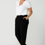 Size 12 woman wears jersey work pants in black. Styled back with a fuchsia pink v-neck top. Comfortable corporate pants for women. Designed and made in Australia for women sizes 8 - 24. 