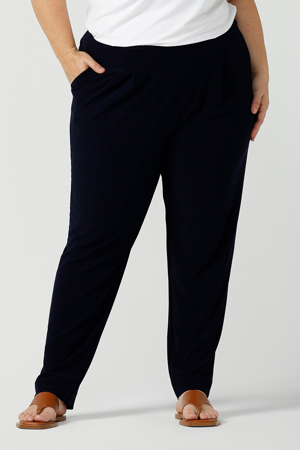 Close up of a curvy size 18 woman wears jersey work pants in navy. Styled back with a white bamboo v-neck top. Comfortable corporate pants for women. Designed and made in Australia for Australian womenswear label Leina & Fleur. Inclusive size range 8 - 24.