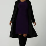 Back view of a size 10 woman wears the Audrey Dress in Amethyst. A purple Jersey dress made for women size 8-24. A comfortable workwear dress for petite to plus size 8-24. Styled back with the Sorel trenchcoat made in Australia for women size 8-24. 