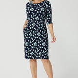 An over 40 woman wears a round neck shift dress in green and blue floral print. A good work wear dress for women, this jersey dress is made in Australia by Australian and New Zealand women's clothes brand, Leina & Fleur. Available in sizes 8 to 24, shop this comfortable work dress in plus size and petite sizes.