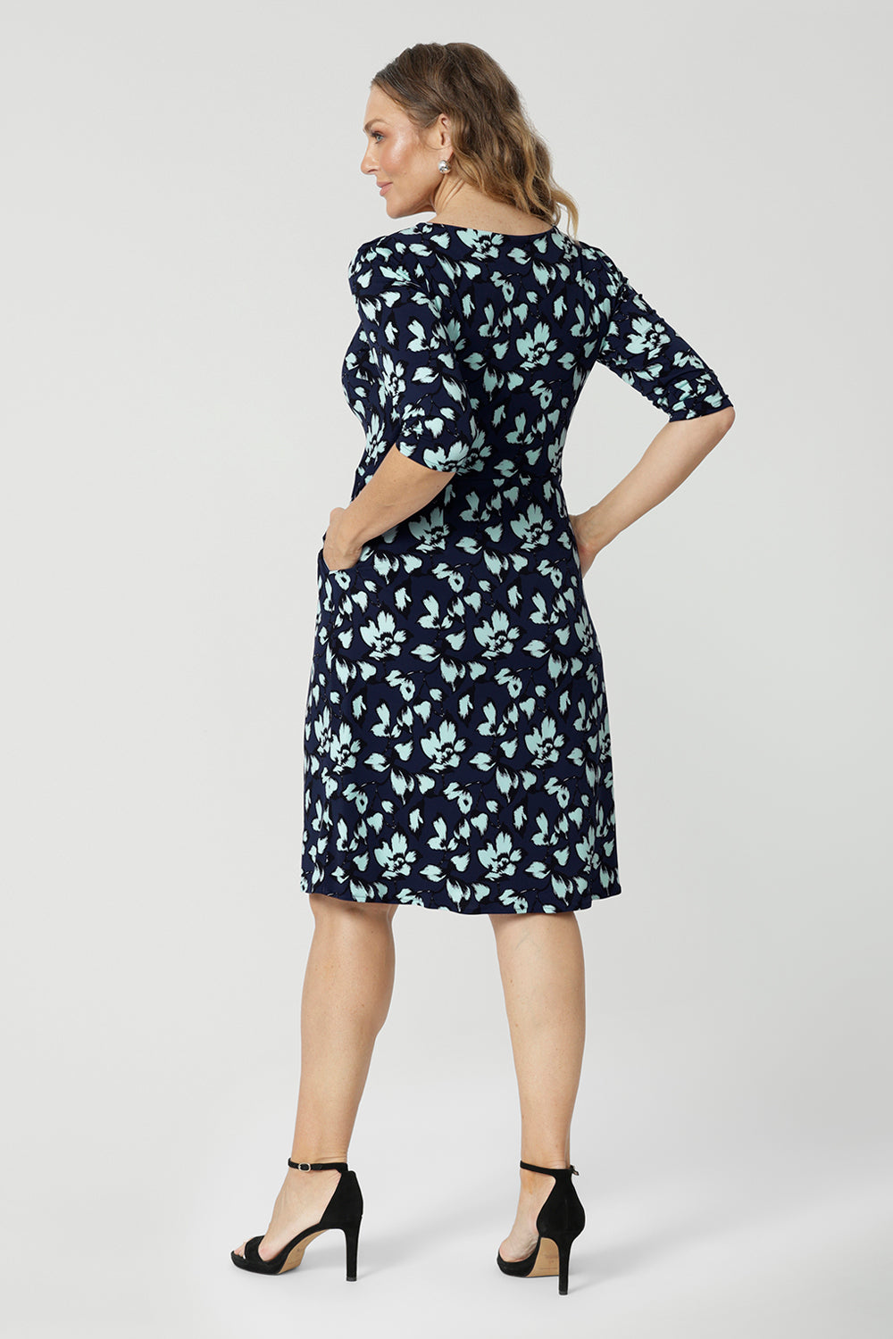 Back view of an over 40 woman wears a round neck shift dress in green and blue floral print. A good workwear dress for women, this jersey dress is made in Australia by Australian and New Zealand women's fashion brand, Leina & Fleur. Available in sizes 8 to 24, shop this easy-care work dress in plus size and petite sizes.