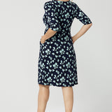 Back view of an over 40 woman wears a round neck shift dress in green and blue floral print. A good workwear dress for women, this jersey dress is made in Australia by Australian and New Zealand women's fashion brand, Leina & Fleur. Available in sizes 8 to 24, shop this easy-care work dress in plus size and petite sizes.