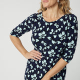 Close up images of an over 40 woman wears a round neck shift dress in green and blue floral print. A good workwear dress for women, this jersey dress is made in Australia by Australian and New Zealand women's clothes label, Leina & Fleur. Available in sizes 8 to 24, shop this comfortable work dress in plus size and petite sizes.