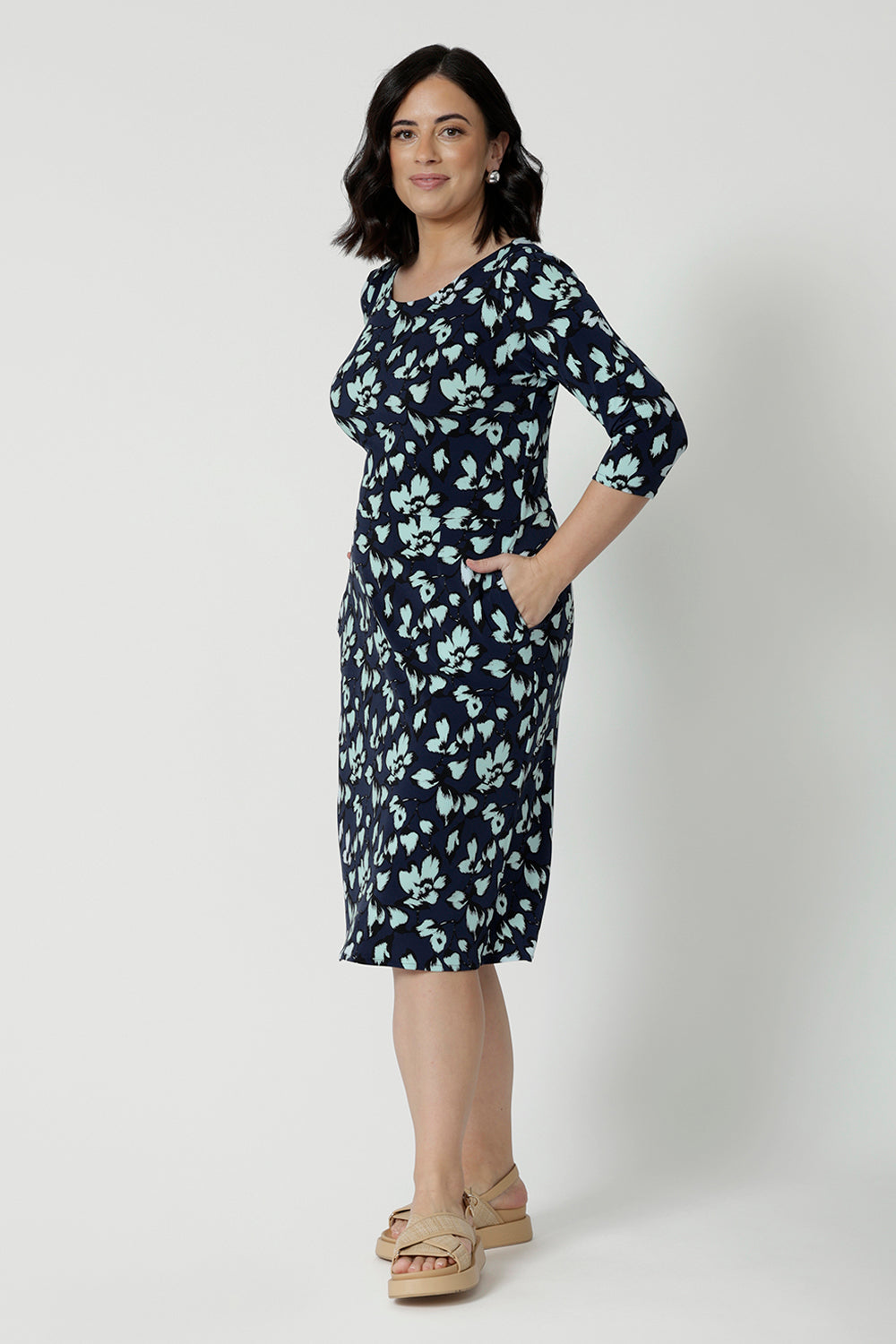 Showing a good dress for petite height women, a size 12 woman wears a round neck shift dress in green and blue floral print. A good workwear dress for women, this jersey dress is made in Australia by Australian and New Zealand women's fashion brand, Leina & Fleur. Available in sizes 8 to 24, shop this easy-care work dress in plus size and petite sizes.