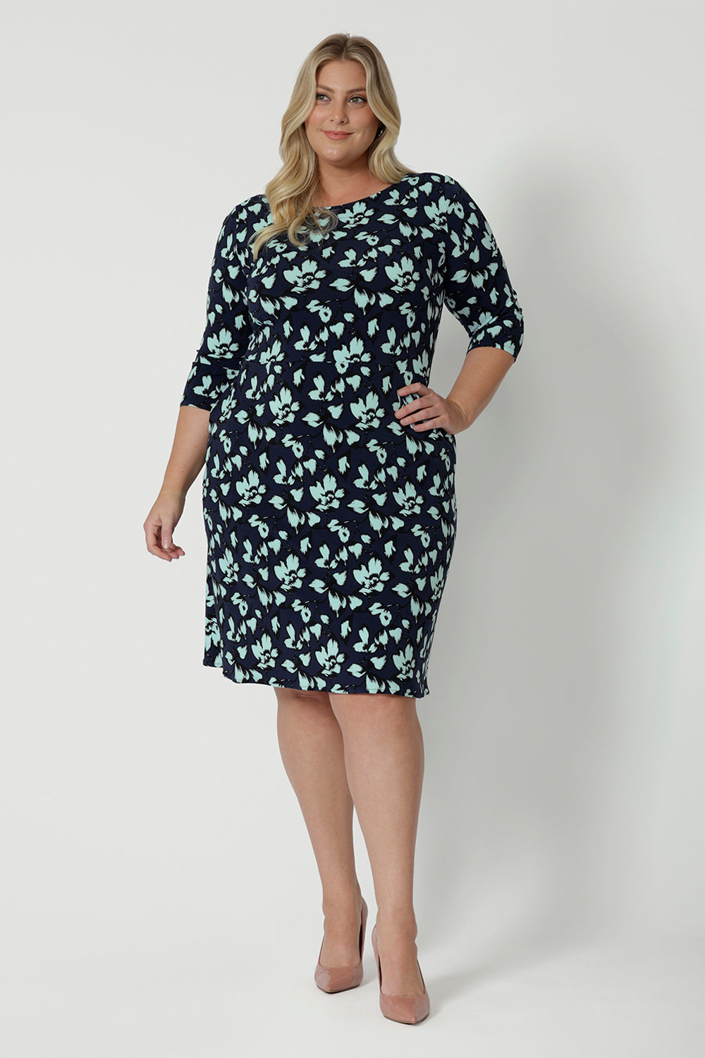 A size 18 woman wears a round neck plus size shift dress in green and blue floral print. A good workwear dress for women, this jersey dress is made in Australia by Australian and New Zealand women's fashion brand, Leina & Fleur. Available in sizes 8 to 24, shop this easy-care work dress in plus size and petite sizes.