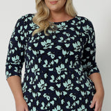 Close up of a size 18 woman wearing a round neck plus size shift dress in green and blue floral print. A good workwear dress for women, this jersey dress is made in Australia by Australian and New Zealand women's clothing brand, Leina & Fleur. Available in sizes 8 to 24, shop this easy-care work dress in plus size and petite sizes.