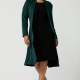 Green Sorel coast in a size 10 woman wears the Audrey Dress, a black jersey round neckline dress with pockets and a boat neckline. Knee length style and easy care workwear for women. Made in Australia for women size 8 - 24.