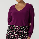 A size 10 woman wears the Avery top in Magenta, a long sleeve top with balloon sleeves and cuff detail. Soft v-neeckline and gathered back yoke. Made in Australia for women size 8 - 24. 