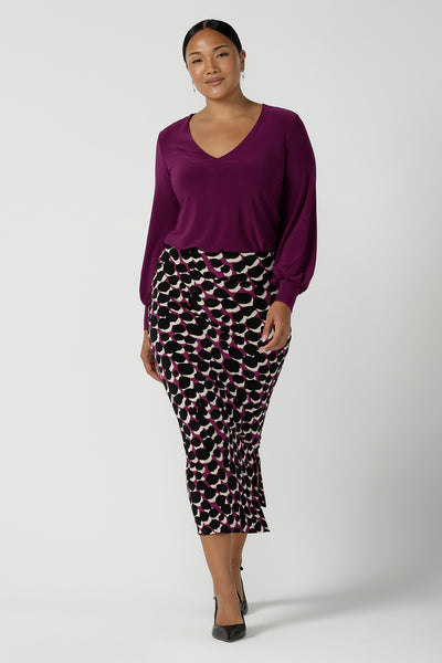 A size 10 woman wears the Avery top in Magenta, a long sleeve top with balloon sleeves and cuff detail. Soft v-neeckline and gathered back yoke. Made in Australia for women size 8 - 24. Styled back with the Andi Tube Skirt in Alula.