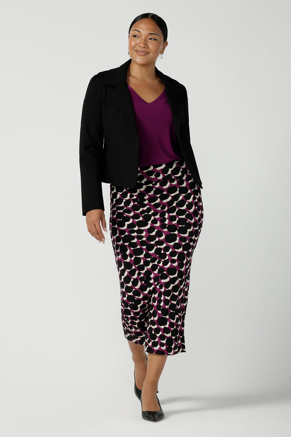 A size 10 woman wears the Avery top in Magenta, a long sleeve top with balloon sleeves and cuff detail. Soft v-neeckline and gathered back yoke. Made in Australia for women size 8 - 24. Styled back with the Andi Tube Skirt in Alula.