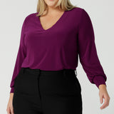 A size 18 woman wearing the Avery top in Magenta. A soft v-neck top with balloon sleeves and cuff detail. Made in Australia for women size 8 - 24. 