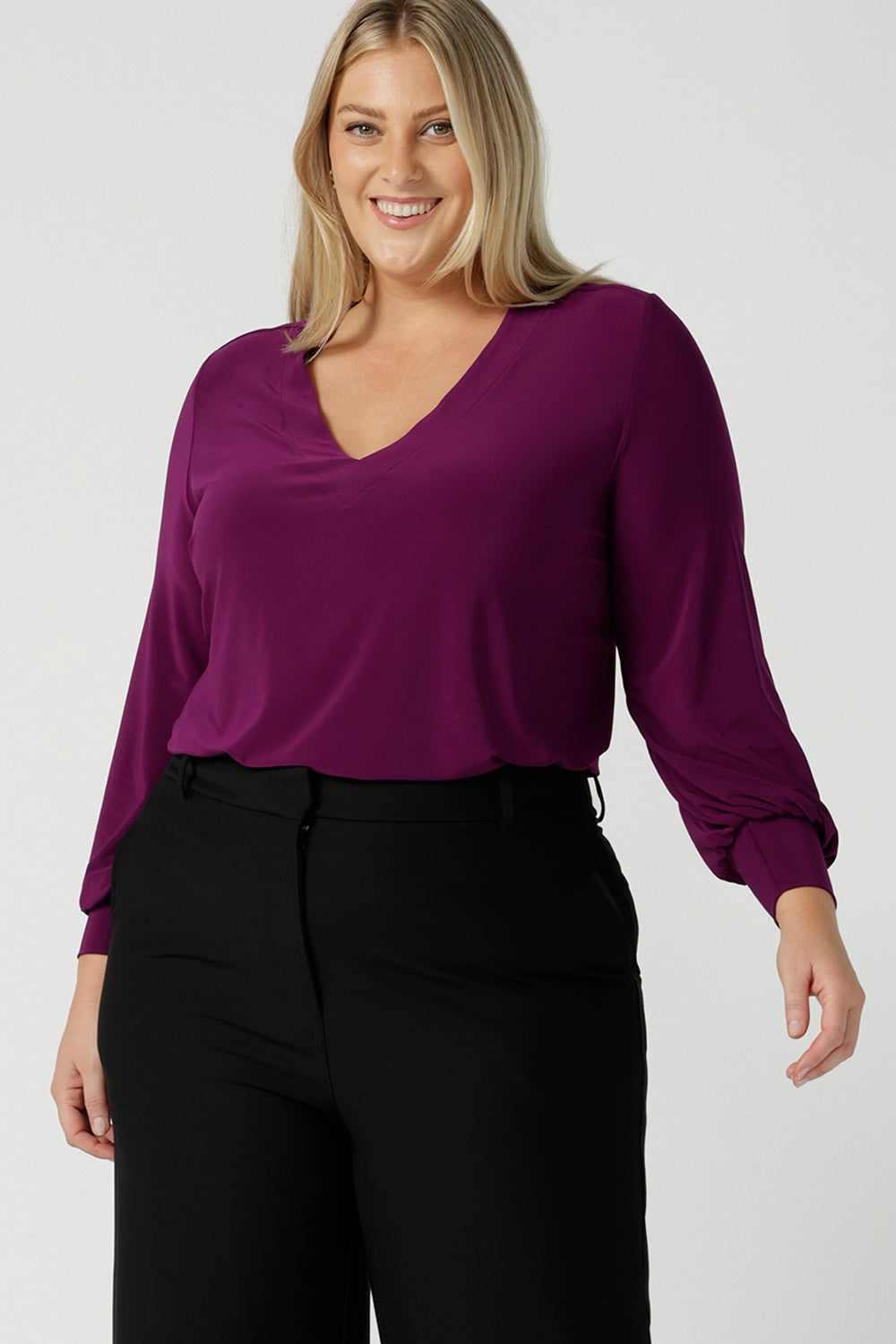 A size 18 woman wearing the Avery top in Magenta. A soft v-neck top with balloon sleeves and cuff detail. Made in Australia for women size 8 - 24. 