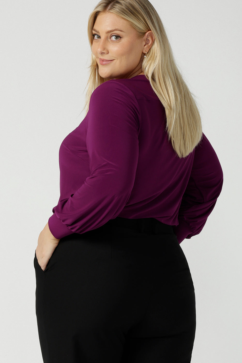 Back view of a size 18 woman wearing the Avery top in Magenta. A soft v-neck top with balloon sleeves and cuff detail. Made in Australia for women size 8 - 24.