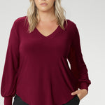 The Avery Top in Ruby brings effortless elegance to your everyday wardrobe, combining tailored structure with luxurious comfort. Crafted in Australia from a soft-stretch, dry-touch jersey fabric, this vibrant red women's top delivers both style and wearability. The semi-fitted silhouette features long bell sleeves with cuffs that add a touch of drama, while still maintaining a polished, versatile look.