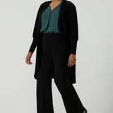 A size 10 woman wears the Bardon Duster in Black, a jersey cardigan with balloon sleeves and made in comfortable jersey. Petite to plus size and styled back with the Terry top in Alpine Tencel. 