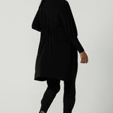 Back view of a size 10 woman wearing the Bardon Duster in Black, a jersey cardigan with balloon sleeves and made in comfortable jersey. Petite to plus size and styled back with the Bardon Duster in Black. And amethyst top.