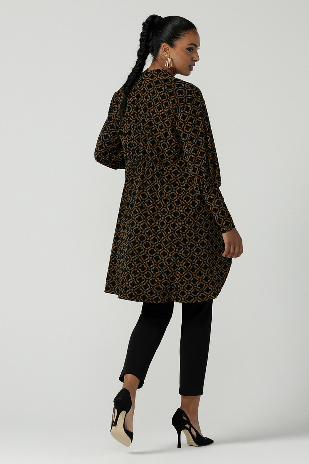 Back view of a size 10 woman wearing the Bardon Duster in Zellige. A jersey longline cardigan with extended balloon sleeves and a curved hemline. Made in Australia for women size 8-24. In a beautiful tile print design with brown and black details.