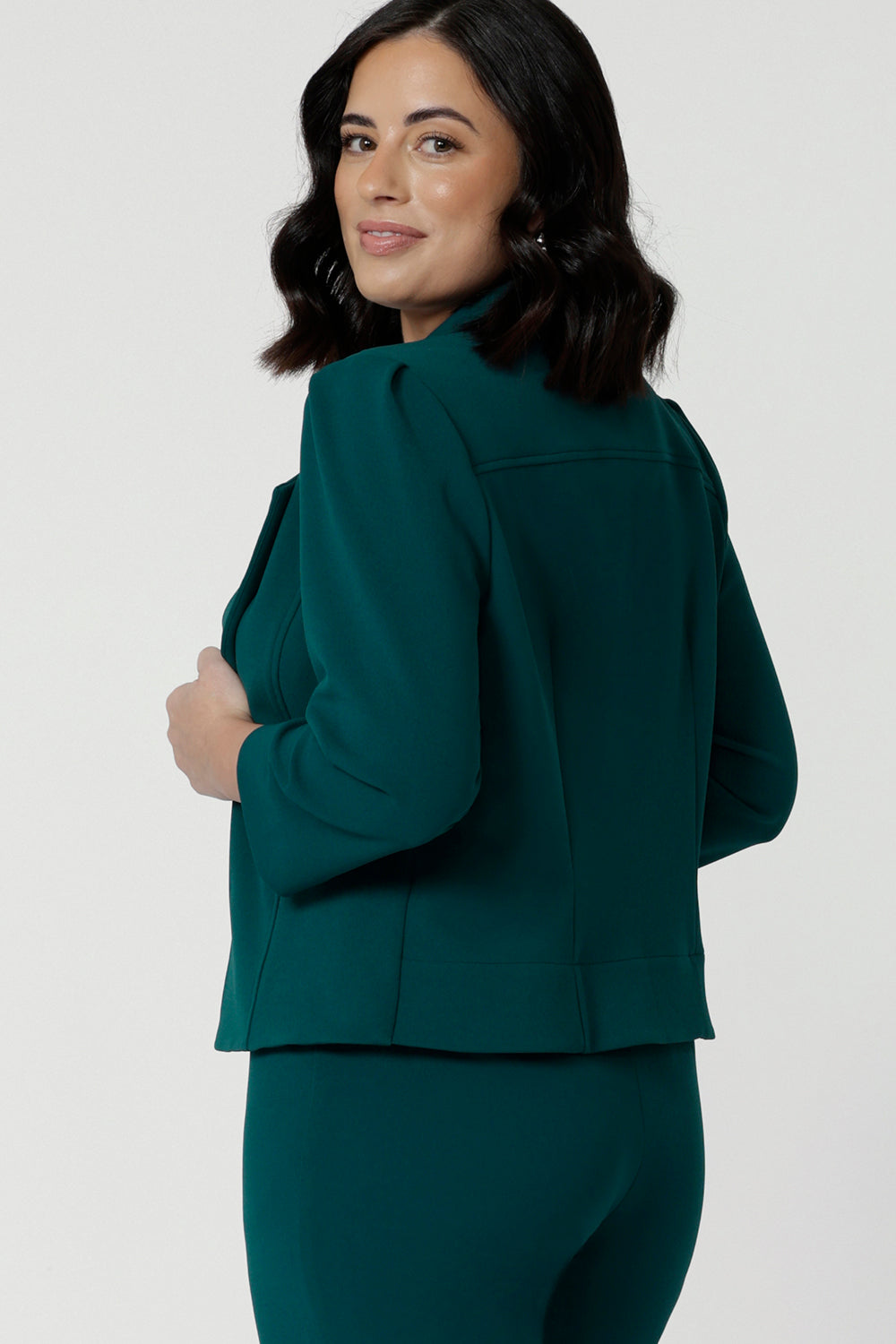 Side view of a great workwear jacket for petite height women. The Benni 3/4 sleeve jacket is worn with tapered leg green workwear pants.
A cropped green jacket , it makes a good workwear suit for women. In sizes 8 to 24, this is a women's jacket  for plus size to petite height women by Australian and New Zealand women's clothing brand, Leina & Fleur.