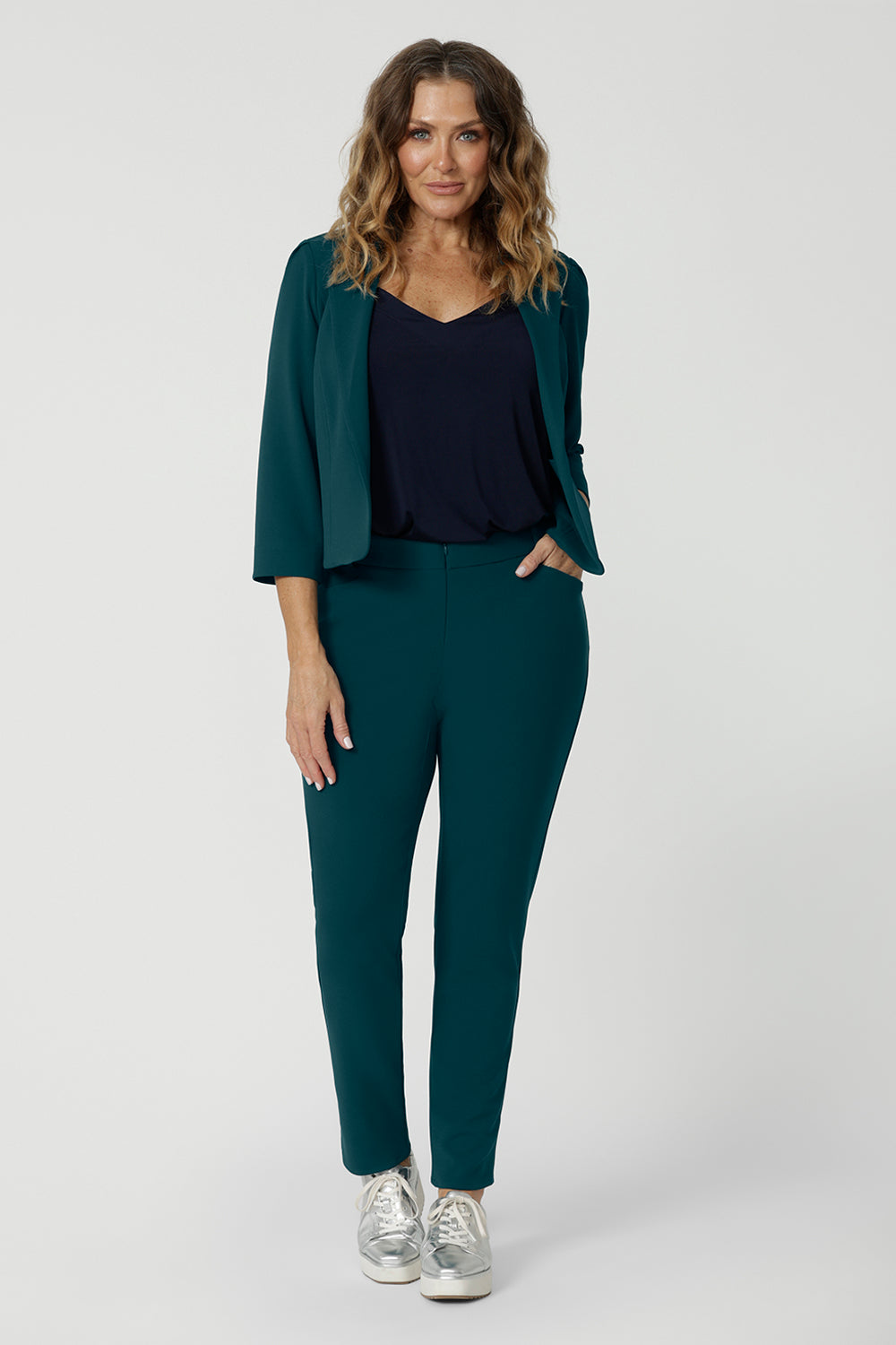 A good workwear outfit for over 40 women, a size 12 woman wears a cropped jacket in green scuba crepe jersey with a navy cami and tapered leg, green pants. Good pants for work, these trousers are made from stretchy jersey and are comfortable for all-day wear. Made in Australia by Australian and New Zealand women's clothes brand, Leina & Fleur, shop easy-care workwear for petite to plus size women. 