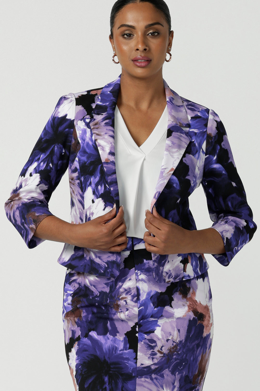 A size 10 woman wears a Benni Jacket in Jacaranda. With 3/4 sleeves and a floral purple print. Made in Australia for a size inclusive fashion label Leina & Fleur size 8-24.