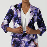 A size 10 woman wears a Benni Jacket in Jacaranda. With 3/4 sleeves and a floral purple print. Made in Australia for a size inclusive fashion label Leina & Fleur size 8-24.