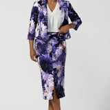 Back view of a size 10 woman wears the Aaron Midi Skirt in Jacaranda. A printed Midi length skirt in purple florals. Made in Australia for women size 8-24. Styled back with pink pumps and a purple Jacaranda jacket. 