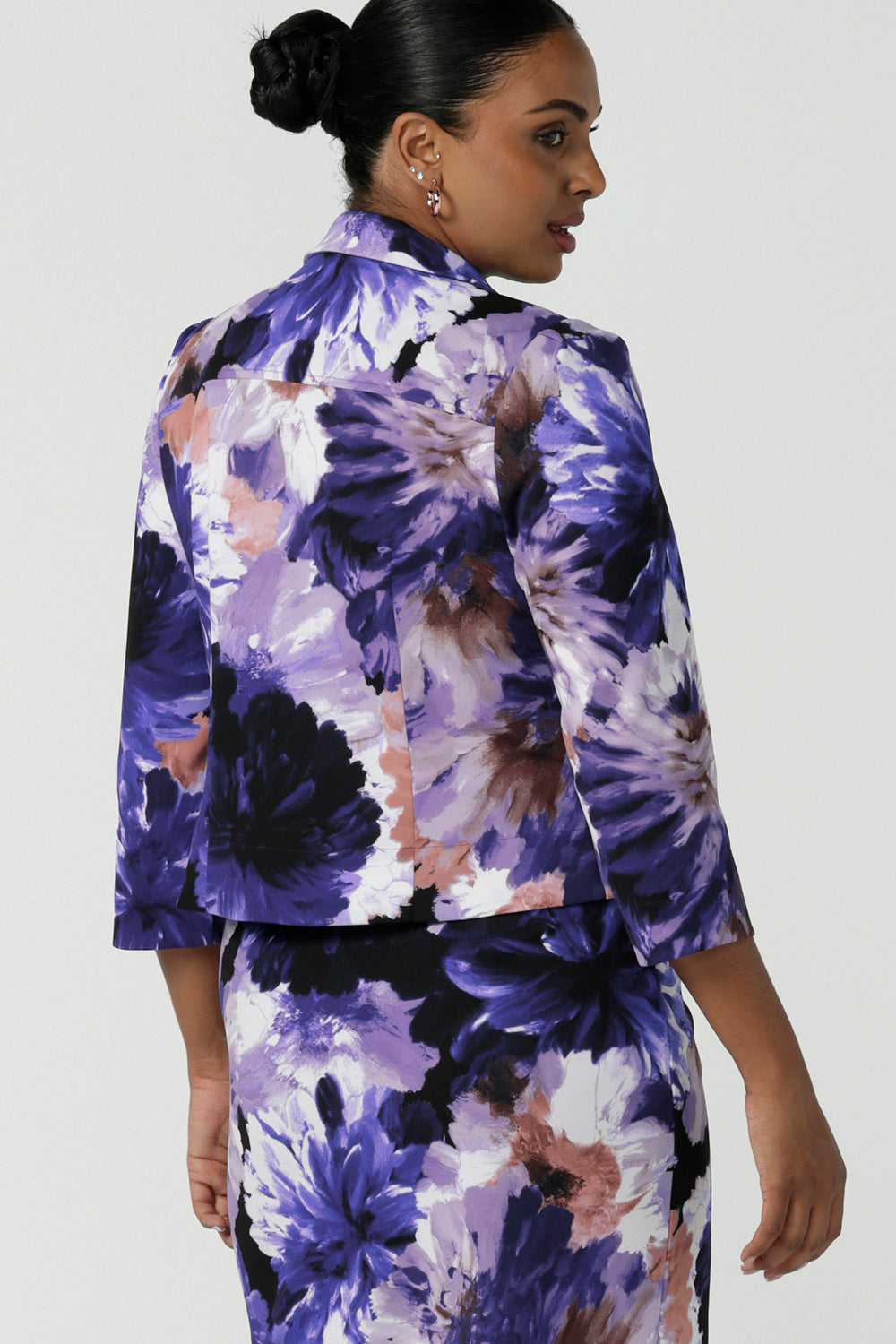 Back view of a size 10 woman wears a Benni Jacket in Jacaranda. With 3/4 sleeves and a floral purple print. Made in Australia for a size inclusive fashion label Leina & Fleur size 8-24.