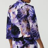 Back view of a size 10 woman wears a Benni Jacket in Jacaranda. With 3/4 sleeves and a floral purple print. Made in Australia for a size inclusive fashion label Leina & Fleur size 8-24.