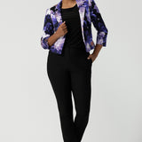 A size 10 woman wears a Benni Jacket in Jacaranda. With 3/4 sleeves and a floral purple print. Made in Australia for a size inclusive fashion label Leina & Fleur size 8-24.