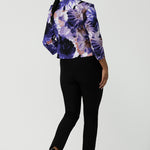 Back view of a size 10 woman wears a Benni Jacket in Jacaranda. With 3/4 sleeves and a floral purple print. Made in Australia for a size inclusive fashion label Leina & Fleur size 8-24.
