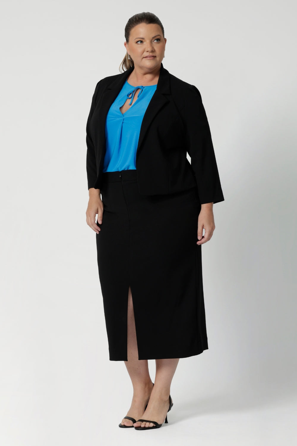 Size 18 woman wears black jacket that contours to the body for a flattering shape. A shoulder yoke further refines the jacket's structure, while the 3/4 length sleeves with tucks at the sleeve heads add a unique, sophisticated detail that sets the jacket apart from traditional blazers.