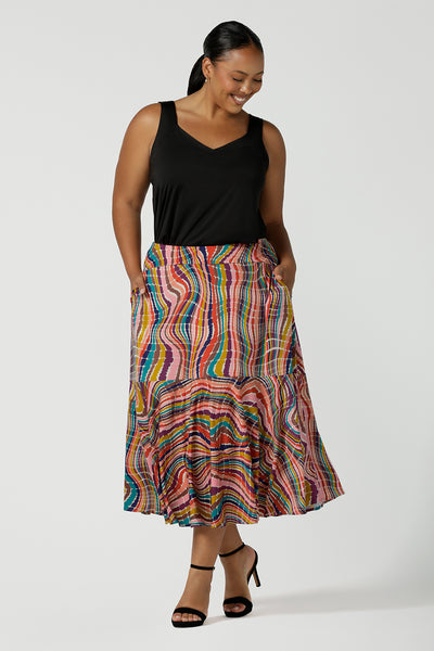Curvy size 16 woman wears Berit Maxi skirt in Kaleidoscope. A rainbow coloured print with The Kaleidoscope print features a vibrant swirl of colour in all colours of the rainbow, pink, red, yellow, turquoise, brown and cobalt on a white base. Made in Australia for women size 8-24.