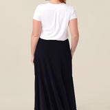 Back view of a a woman wearing a pull on, navy maxi skirt with ruffle hemline with a short sleeve bamboo jersey top in white. This black maxi skirt is a good workwear skirt or smart-casual skirt. Made in Australia in petite plus sizes for all curve of women's bodies..