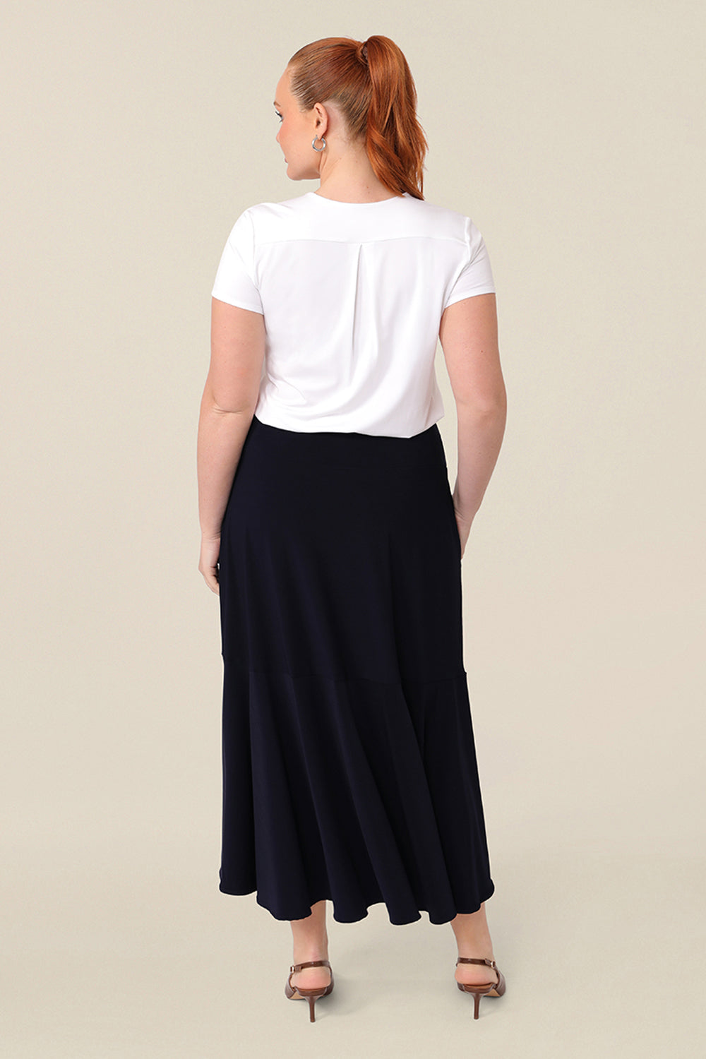Back view of a a woman wearing a pull on, navy maxi skirt with ruffle hemline with a short sleeve bamboo jersey top in white. This black maxi skirt is a good workwear skirt or smart-casual skirt. Made in Australia in petite plus sizes for all curve of women's bodies..