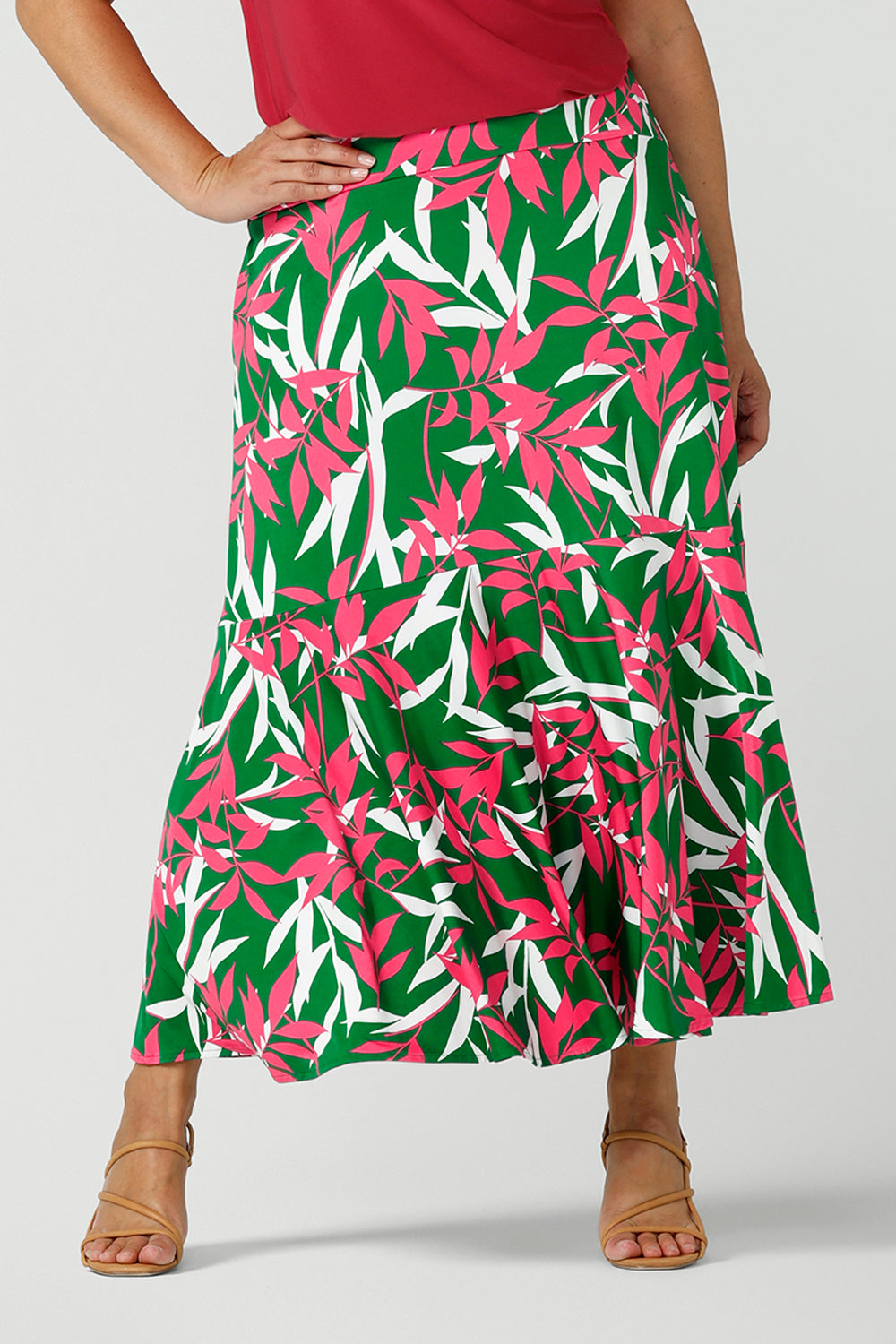 Close up of a size 12 happy woman wears a green jersey skirt with a leaf print. On a verdant green base in a soft jersey fabric. Made in Australia for women size 8 - 24.