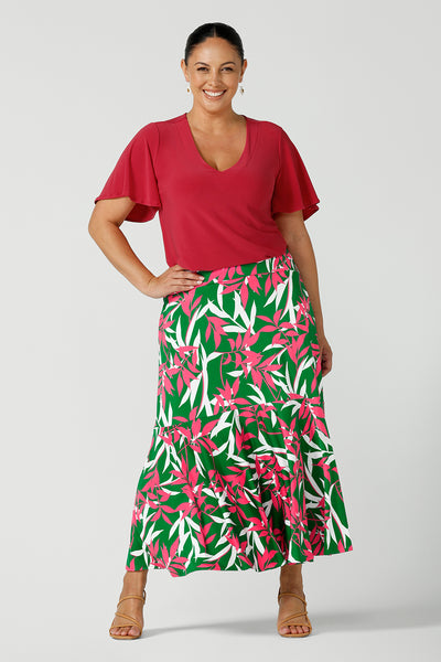 Size 12 happy woman wears a green jersey skirt with a leaf print. On a verdant green base in a soft jersey fabric. Made in Australia for women size 8 - 24.