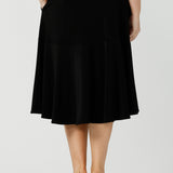 Back view of good workwear skirt for women. This knee-length, pull-on black skirt has pockets, a ruffle hemline and comfort waistband. A great addition to your capsule wardrobe, this black skirt is made by Australian made women's clothing brand, Leina & Fleur. Shop petite to plus size skirts in their online boutique in Australia. 