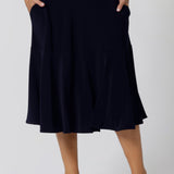 A great example of Australian-made skirts, this navy blue knee-length skirt in comfortable jersey fabric is shown in a size 12 as workwear for curvy women. Available from Australian ladies clothing brand, Leina & Fleur, this classic navy skirt is available as petite to plus size office wear in their online boutique.