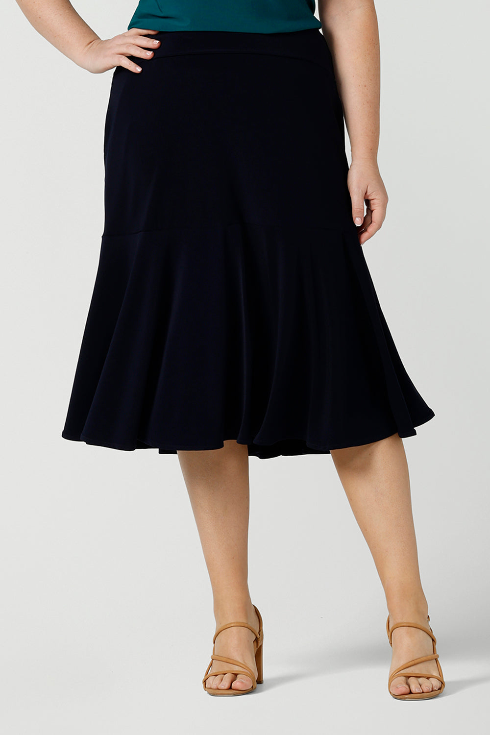 A great example of Australian-made skirts, this navy blue knee-length skirt in comfortable jersey fabric is shown in a size 12 as workwear for curvy women. Available from Australian ladies clothing brand, Leina & Fleur, this classic navy skirt is available as petite to plus size office wear in their online boutique.