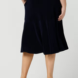 Back view of an Australian-made skirt by New Zealand and Australian women's clothing brand, Leina & Fleur. This navy blue knee-length skirt in comfortable jersey fabric is shown in a size 12 as workwear for curvy women. Available from their online boutique in Australia, this classic navy skirt is available as petite to plus size office wear thanks to their size range of sizes 8, 10, 12, 14, 16, 18, 20, 22 and 24.