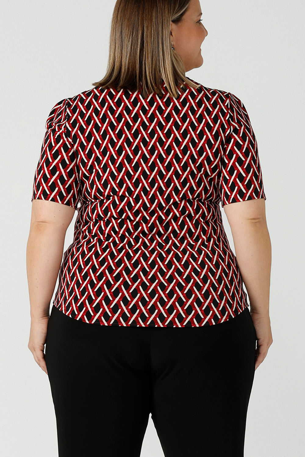 Back view of curvy size 16 woman wears a geometric Chevron print Berni top. Corporate causal work wear top that is comfortable and versatile. Styled back with Black Indi pants. Made in Australia for women size 8 - 24.