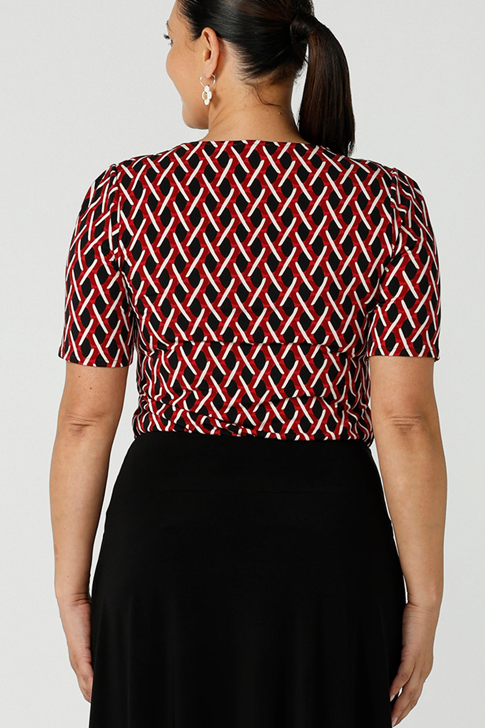 Back view a size 12 woman wears a geometric Chevron print Berni top. Corporate causal work wear top that is comfortable and versatile. Styled back with Black Indi pants. Made in Australia for women size 8 - 24.