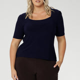 Plus size women wears a casual jersey top in navy blue. This Australian-made women's top has short fitted sleeves, a square neckline, perfect for weekend casual styling and work wardrobes. Available in sizes 8-24. 