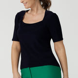 A size 10 over 40 year old woman wears a casual jersey top in navy blue, styled with emerald green pants. This Australian-made women's top has short fitted sleeves, a square neckline and and high-low - perfect for weekend casual and travel capsule wardrobes.