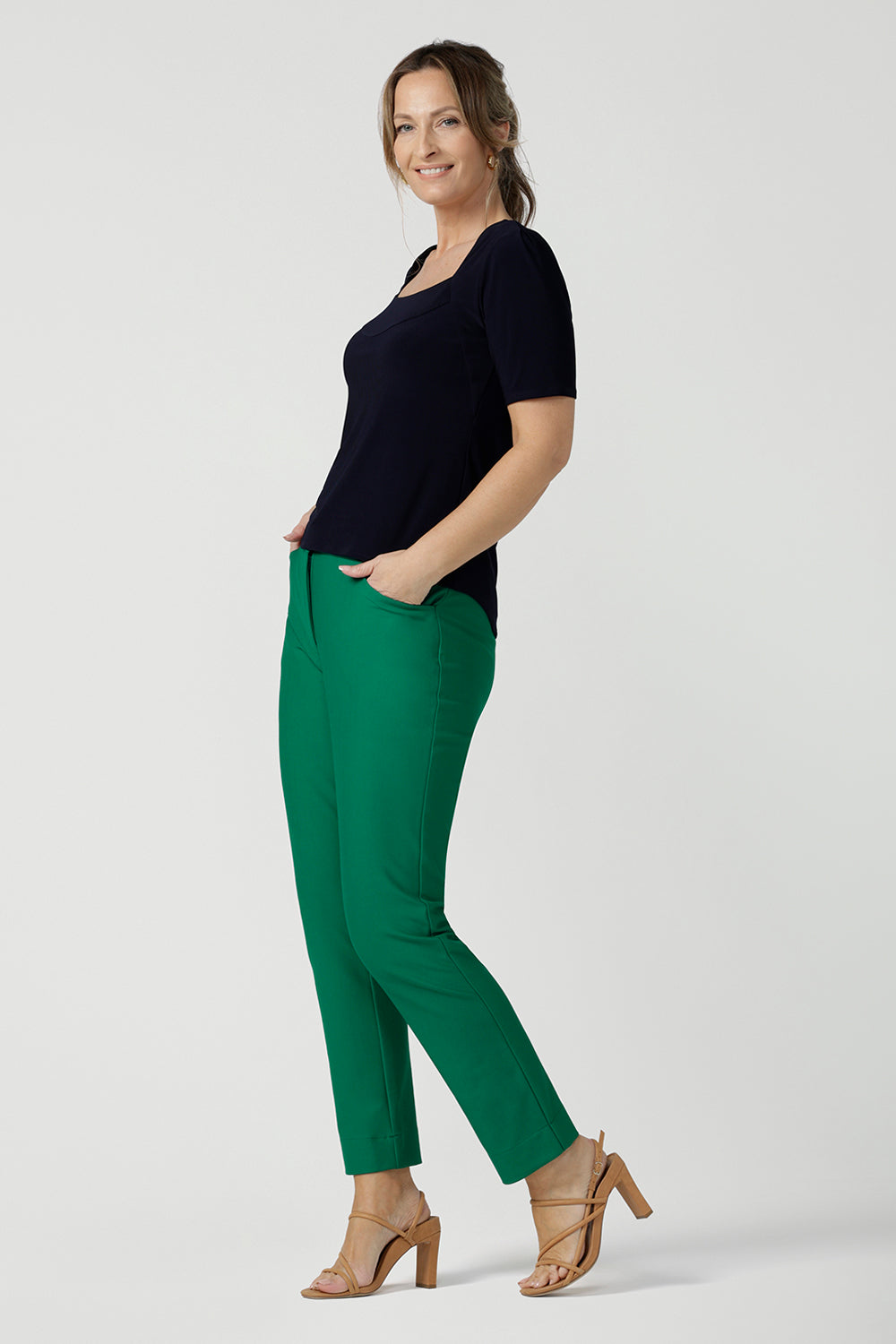 A size 10 over 40 year old woman wears a casual jersey top in navy blue, styled with emerald green pants. This Australian-made women's top has short fitted sleeves, a square neckline and and high-low - perfect for weekend casual and travel capsule wardrobes.