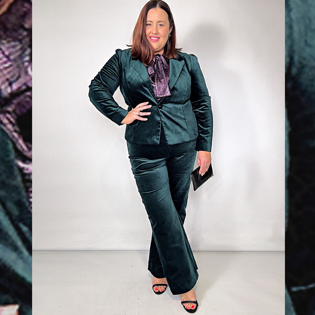 A plus sie woman wears a green velvet cocktail pant suit for a wedding guest outfit.