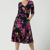 A size 10 Woman wears the Bettina Petite Reversible dress the Celeste print. It is a fixed wrap style with pockets and frill detail. A great work to wedding dress for women size 8 - 24.  